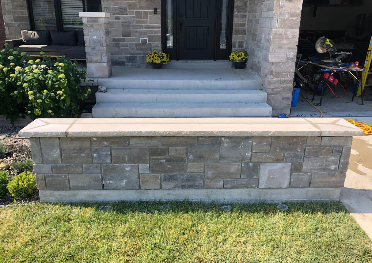 Stone masonry garden wall with limestone caps built by McNamara Masonry in Saint Clair Beach, Tecumseh, Ontario, Canada. Expert masonry services including porch restoration, brick repair, and stonework installation.